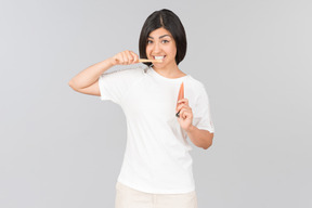 Jovem mulher indiana escovando os dentes e segurando o creme dental