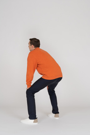 Jeune homme en sweat-shirt orange posant