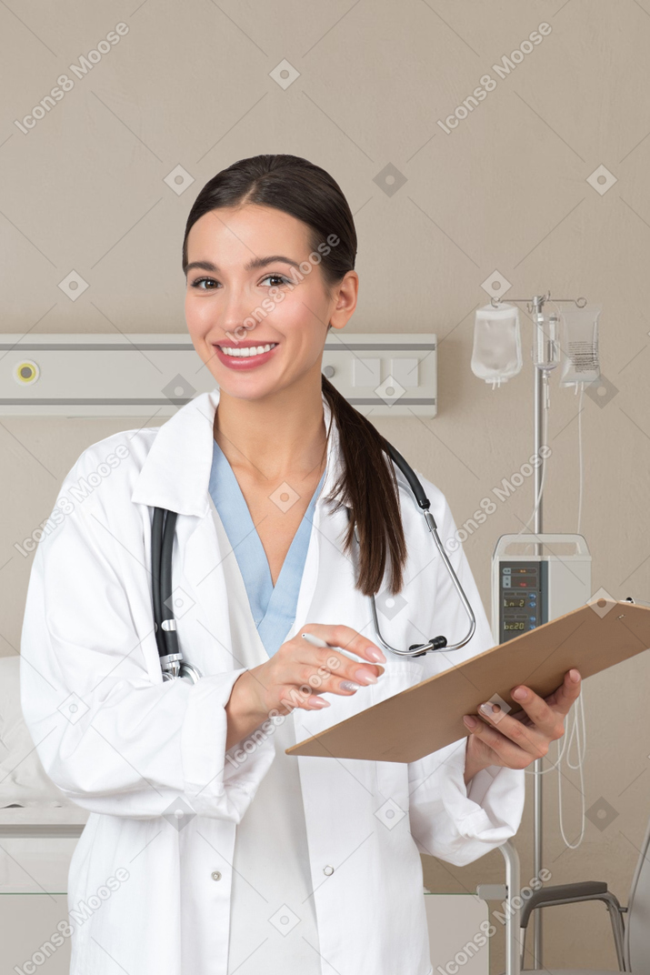 Sorrindo jovem médico permanente na enfermaria médica