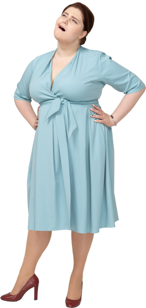 Vista frontale di una donna in abito blu in posa con le mani sui fianchi