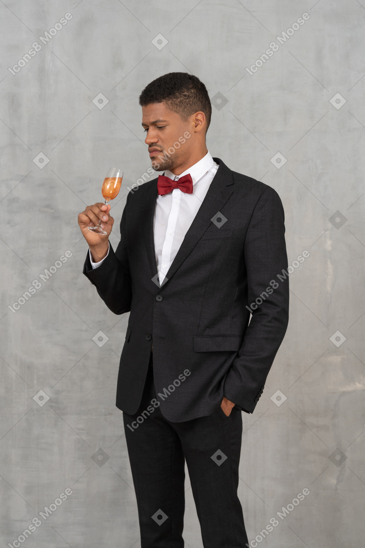 Jeune homme à l'air sérieux debout avec un verre de champagne