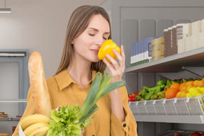 Mulher comprando mantimentos e cheirando um pimentão