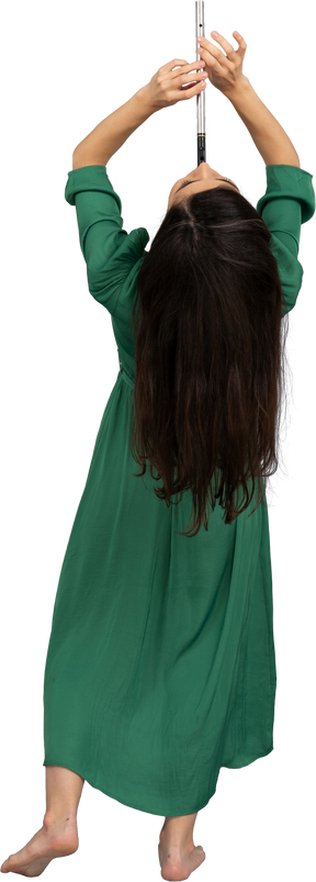 Vista de trás de uma jovem de vestido verde tocando flauta enquanto se inclina para trás