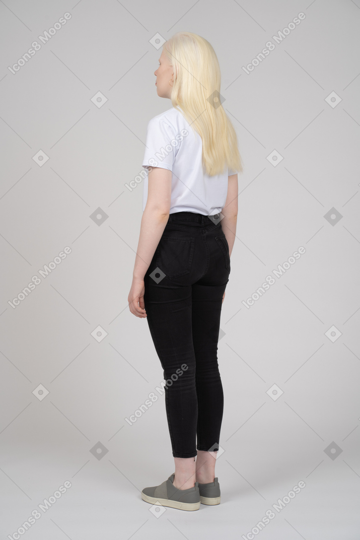 Three-quarter back view of a teenage girl with arms at sides