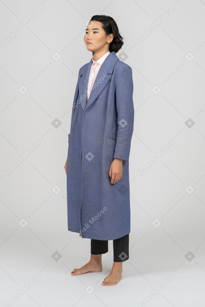 Mujer escéptica con abrigo azul parada