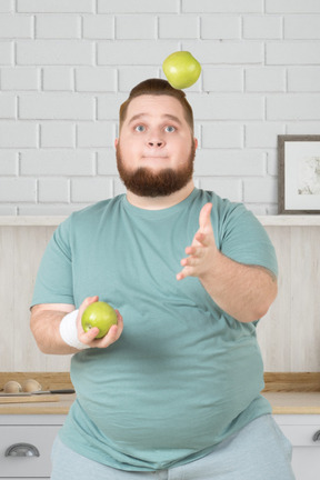 A man juggling apples in a kitchen