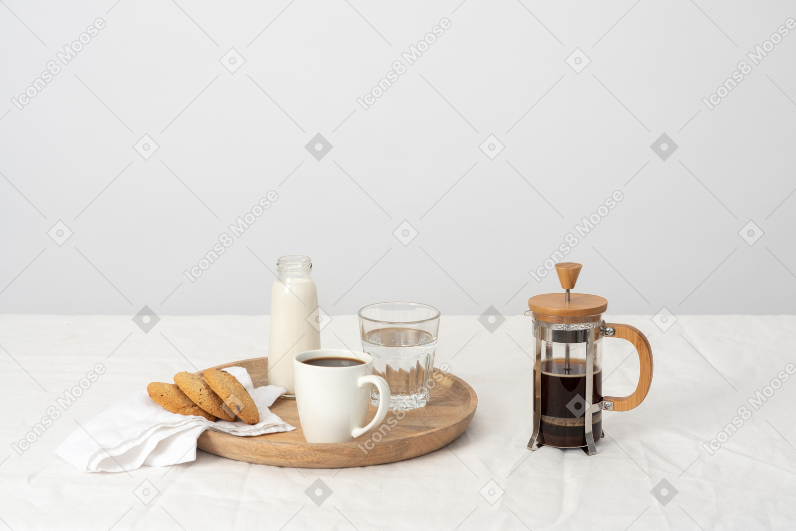 Coffee in french press and large cup of coffee, glass of water, milk and some cookies on the tray