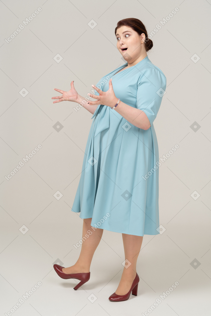 Mulher impressionada de vestido azul em pé de perfil