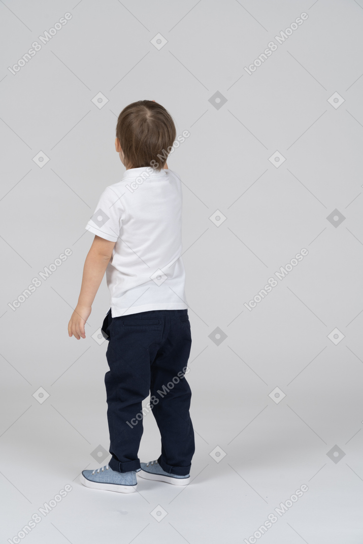 Вид сзади на маленького мальчика, стоящего и отводящего взгляд