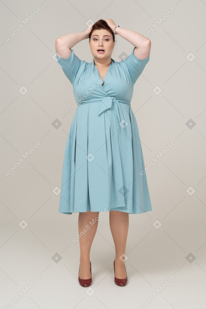 一个身着蓝色连衣裙、双手放在头上的女人的前视图