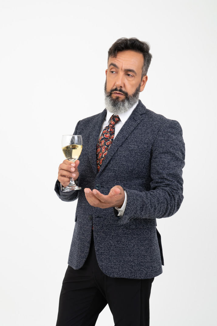 Man in suit with his eyebrow raised holding a glass