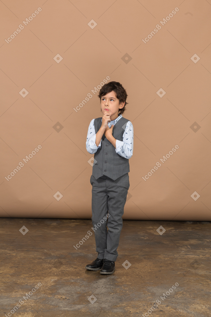 Вид спереди задумчивого мальчика в сером костюме