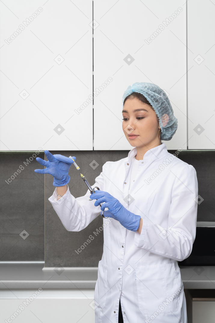 Vista de três quartos de uma enfermeira com um chapéu de médico segurando cuidadosamente uma seringa