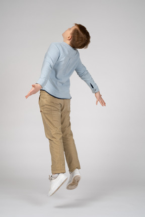 Side view of a boy jumping with his arms outstretched