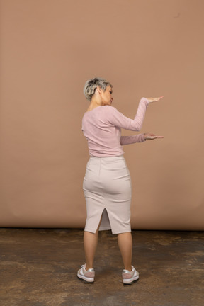 Rear view of a woman in casual clothes showing the size of something