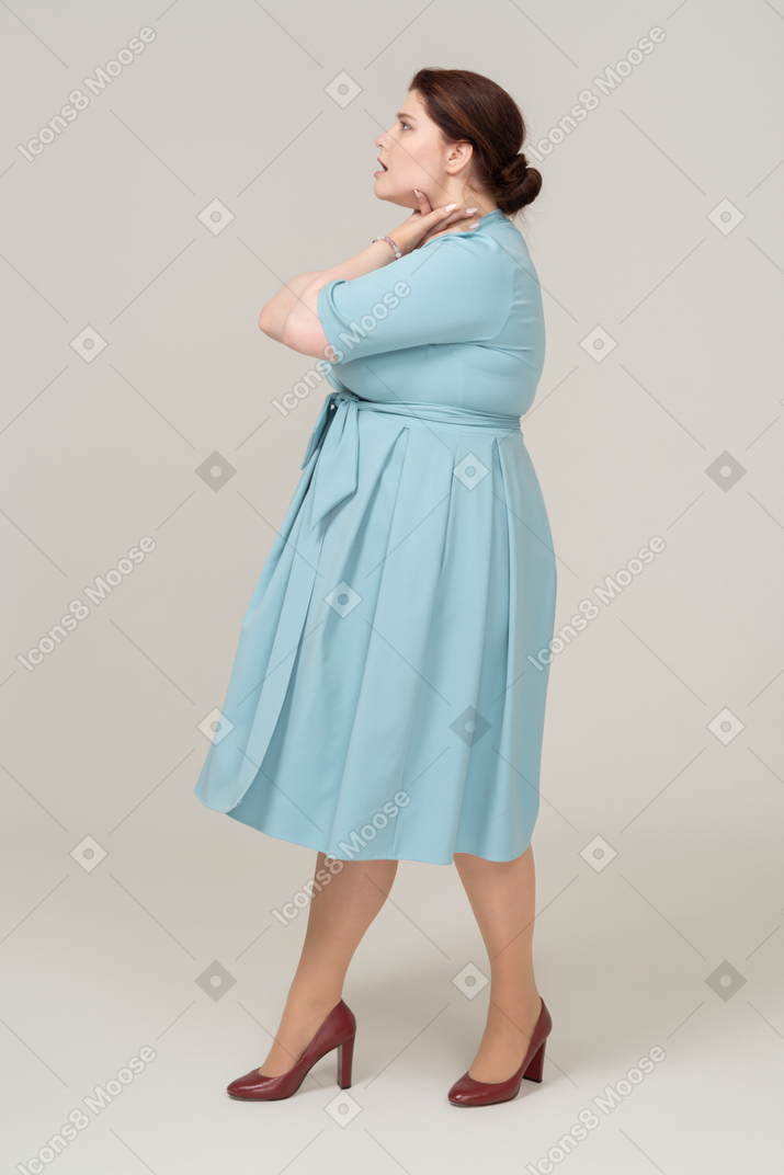 Side view of a woman in blue dress chocking herself