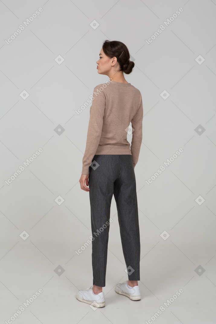 Three-quarter back view of a displeased young lady in pullover and pants