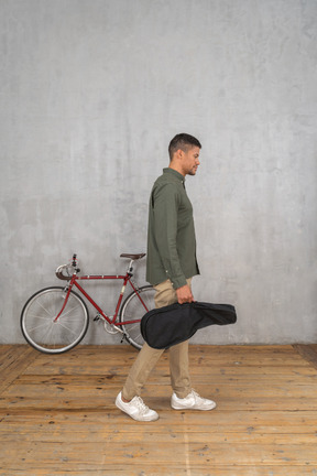 Side view of a man with a ukulele case walking