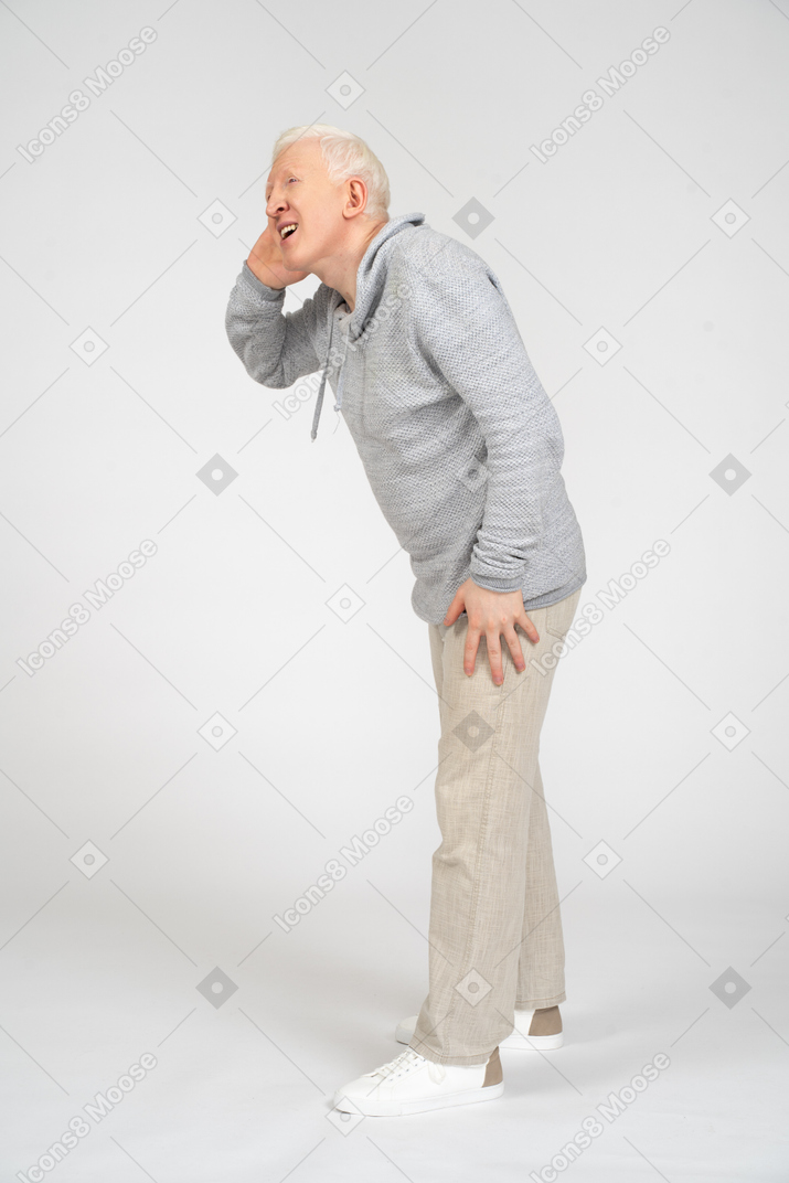 Man standing sideways with hand on his ear