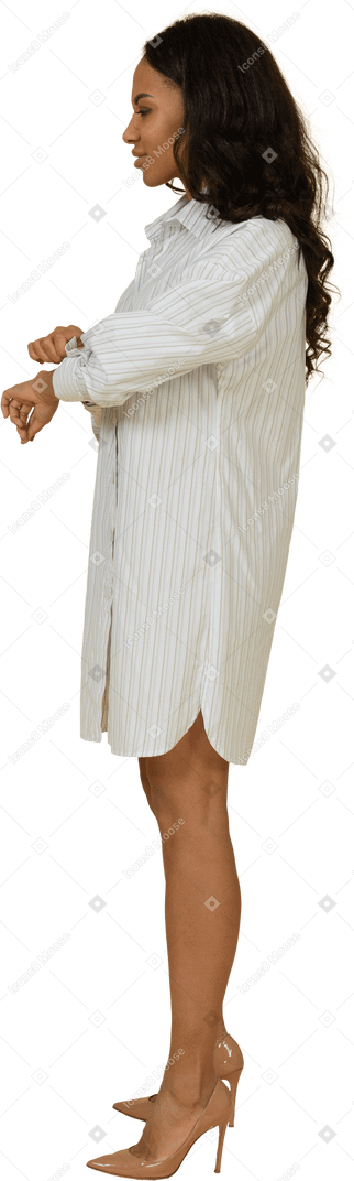 彼女の袖をボタンで留める白いドレスを着た浅黒い肌の若い女性の側面図
