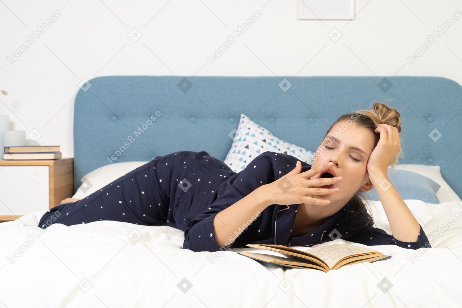 一本打呵欠的年轻女性在床上看书的前视图