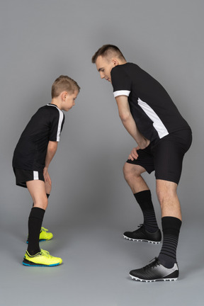 De cuerpo entero de un joven entrenando a un niño pequeño haciendo una estocada