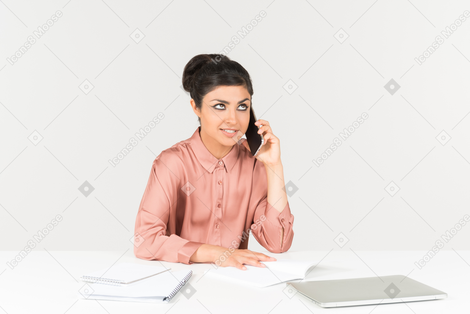Bothered looking young indian woman talking on the phone and working on laptop