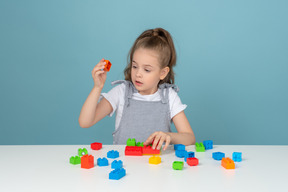 Menina segurando um bloco de lego vermelho