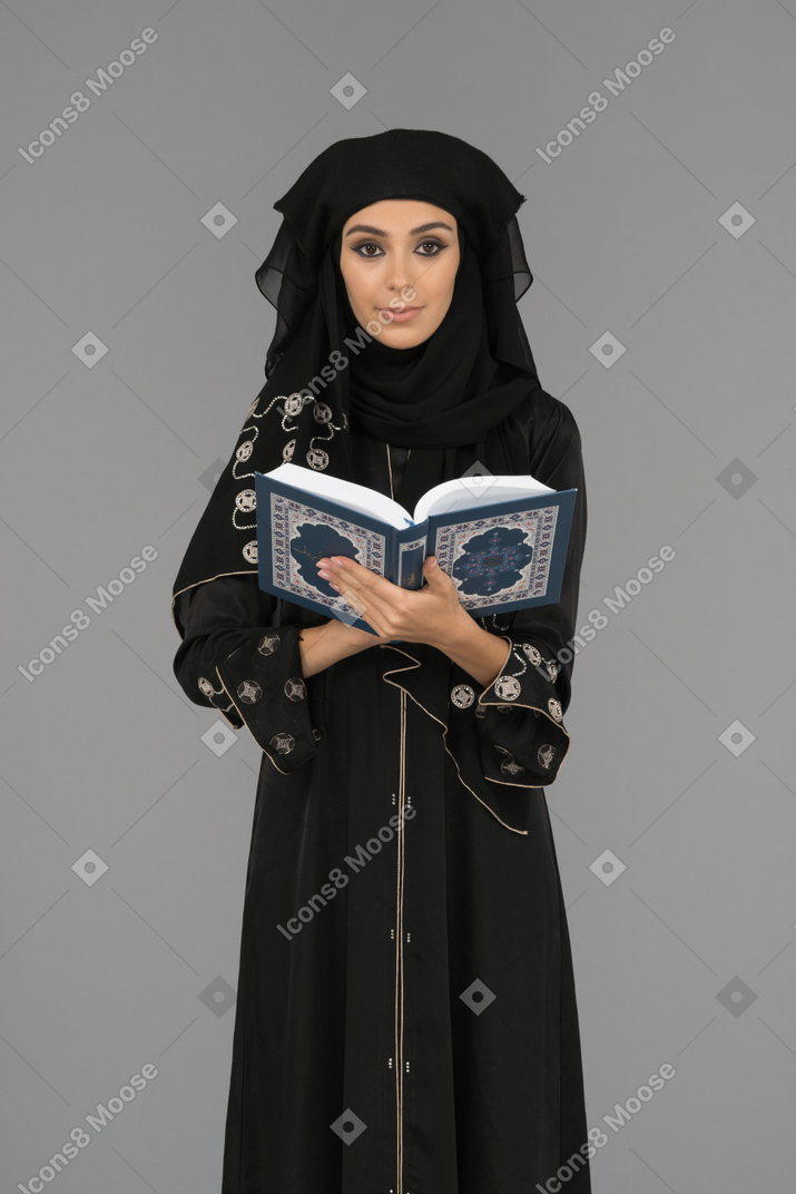 A covered muslim woman holding the quran