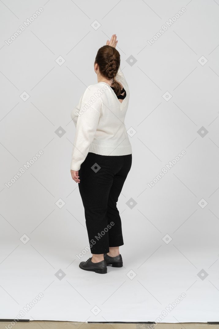 Vista posteriore di una donna grassoccia in abiti casual che saluta qualcuno