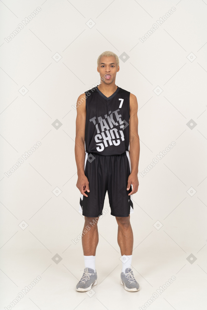 Vista frontal de um jovem jogador de basquete mostrando a língua
