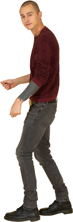 Вид сбоку жестикулирующего молодого человека в красном пуловере