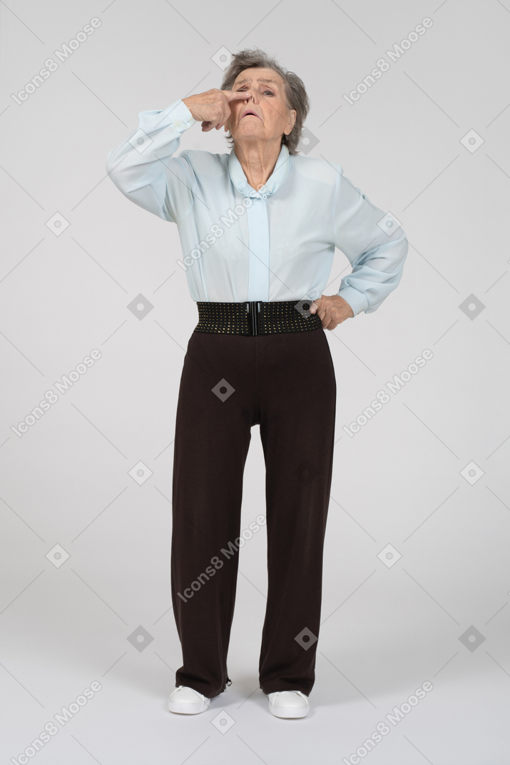Vista frontal de una anciana levantando la nariz con aspecto horrorizado