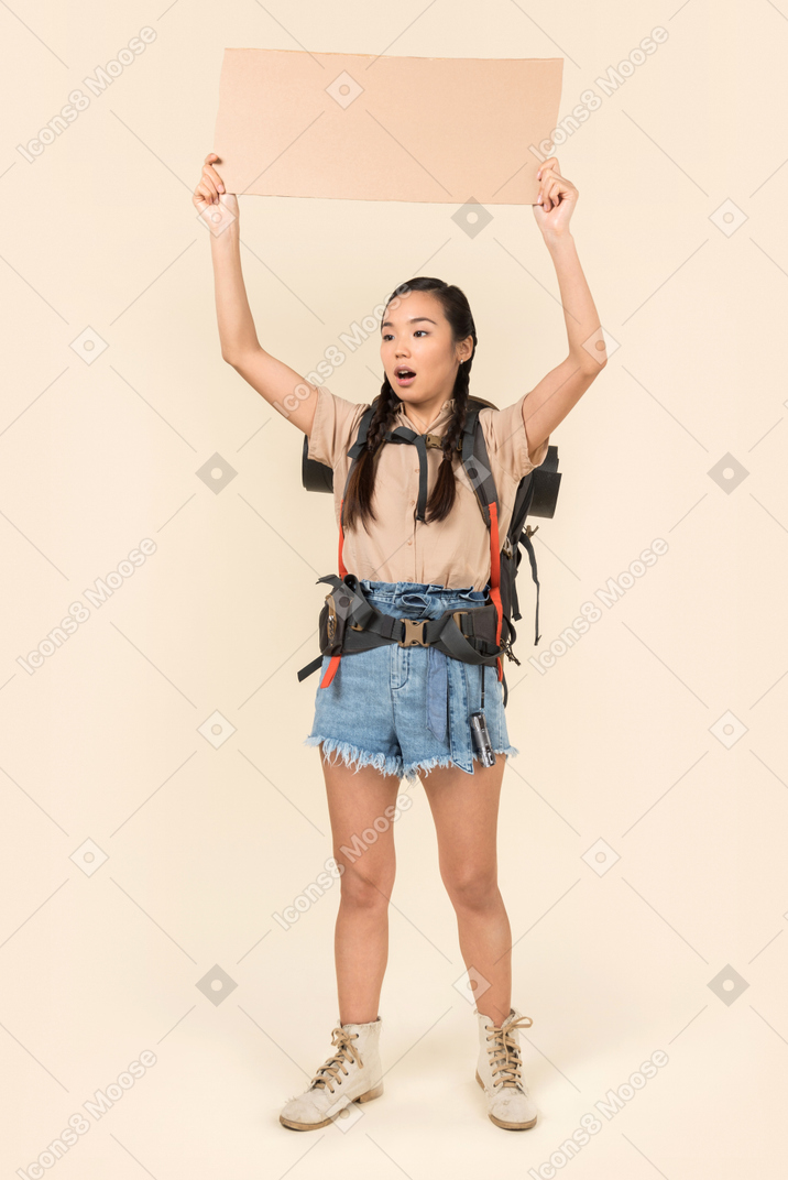 Young female hitchhiker holding up paper card