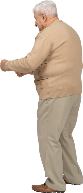 Vista lateral de un anciano feliz con ropa informal de pie con los puños apretados