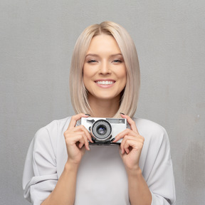 Giovane donna allegra che tiene macchina fotografica d'epoca