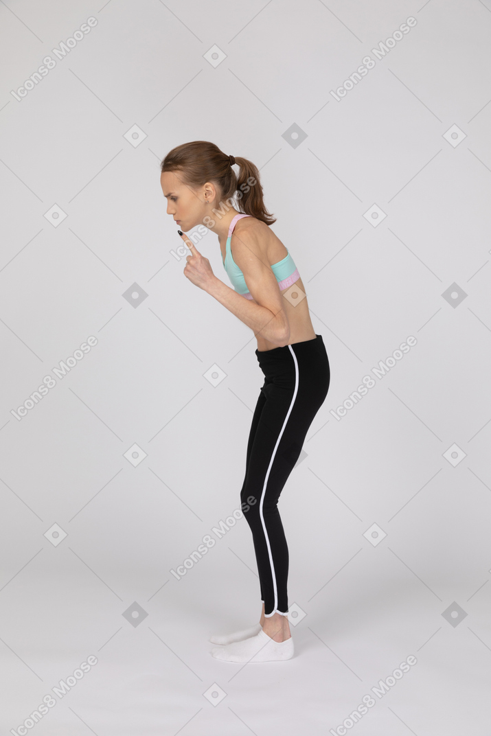 Вид сбоку девушки-подростка в спортивной одежде, поднимающей руку и спорящей