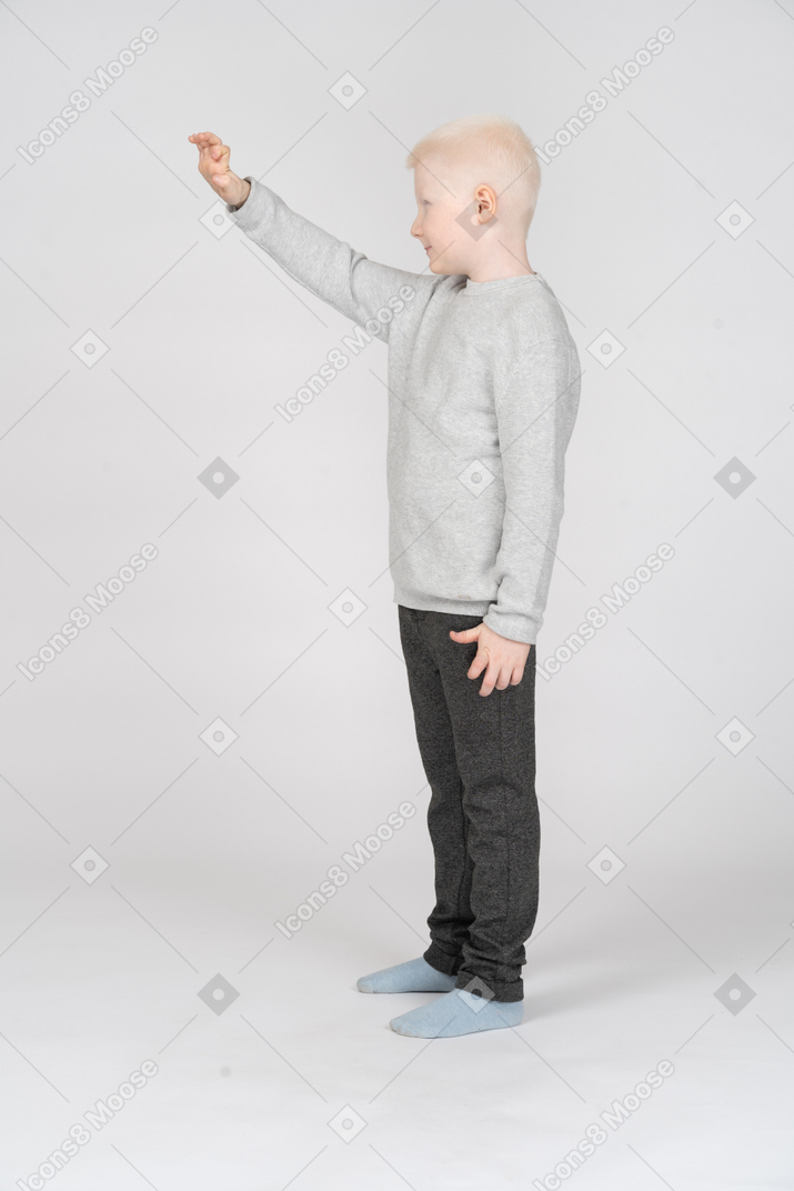 Side view of a boy in casual clothes raising his hand