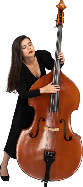 一个年轻的女人，穿着黑色的连衣裙，演奏低音提琴和向前倾斜的前视图