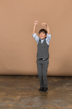 Vista frontal de um menino de terno cinza dançando