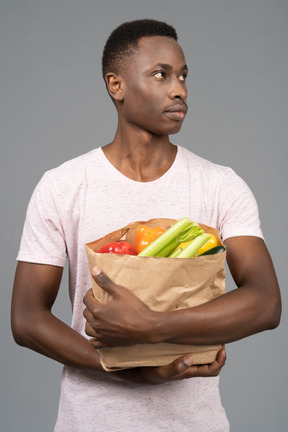 A young man holding a grocery bag