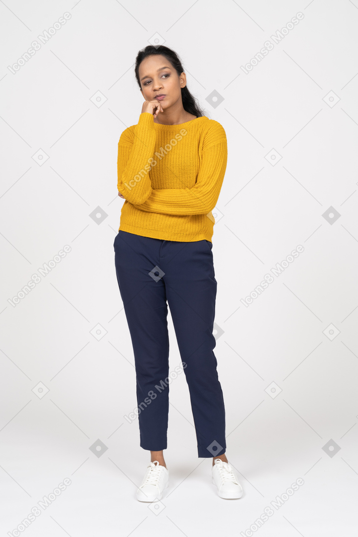 Vista frontal de uma garota pensativa em roupas casuais tocando o queixo com a mão