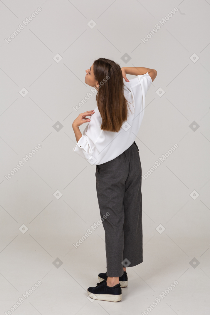 Vista posterior de tres cuartos de una joven en ropa de oficina tocando sus hombros