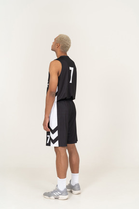 Dreiviertel-rückansicht eines jungen männlichen basketballspielers, der nach oben schaut