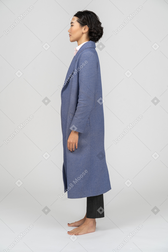 一个穿着蓝色外套的女人站着的侧视图