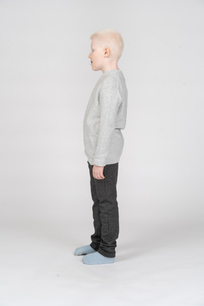 Vista lateral de un niño niño en ropa casual mirando hacia abajo y abriendo la boca
