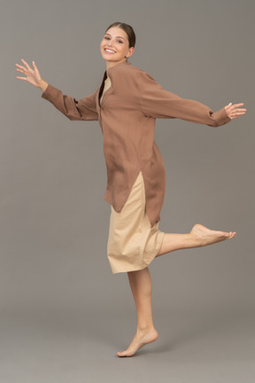 Smiling woman standing barefoot with left leg lifted in the air