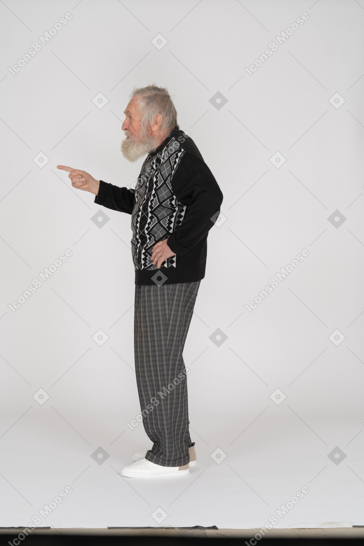 Side view of an old man pointing with his finger to the left