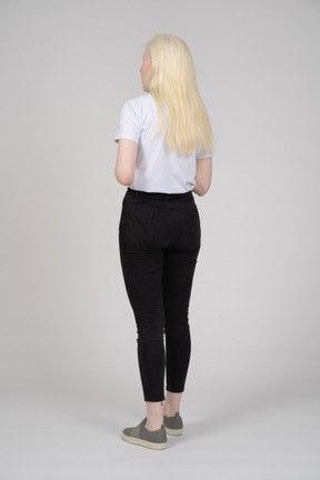 Three-quarter back view of a young blonde woman in casual clothes