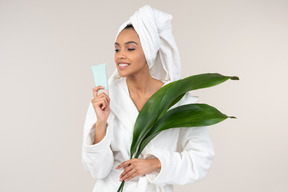 Black woman in white bathrobe and head towel enjoying her skin care routine